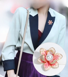 Macro detail of enamel flower brooch featuring a large pearl and sparkling rhinestones