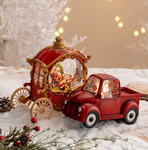 Close-up of lighted Christmas snow globes with vintage red truck and carriage on faux snow