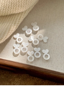 Macro view of heart-shaped silicone earring backs on a rustic beige linen background