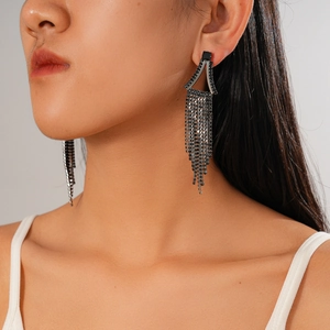 Gros plan de boucles d'oreilles géométriques à franges avec strass noirs sur mannequin