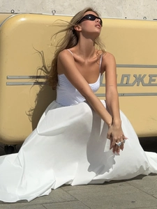 Detail view of white maxi skirt with pleated waist and thin rhinestone camisole top