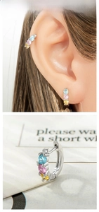 Detail of silver huggie earrings with blue, pink and yellow zircon stones on a model