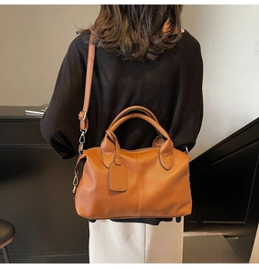 Rear view of model holding a brown lychee pattern leather handbag with gold hardware