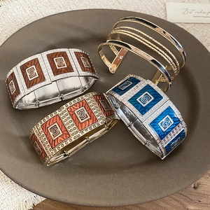 Detailed view of colorful enamel square bracelets with spiral patterns on a display tray