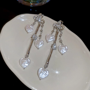 Détails des boucles d'oreilles pompons argentées avec perles baroques et strass brillants