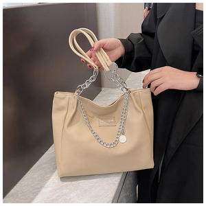 Detail of beige tote bag featuring grainy leather texture and silver chain strap