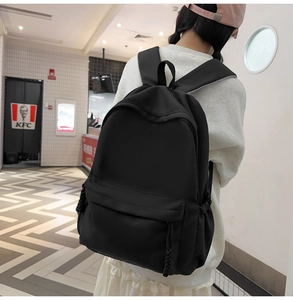 Detail eines großen schwarzen Nylon-Rucksacks mit verstellbaren Kordelzügen und Fronttasche