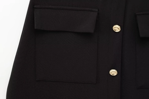 Detail of black dress with gold embossed buttons and symmetrical flap pockets