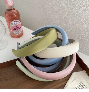 Macro view of wide matte headbands in pastel colors stacked on a wooden tray