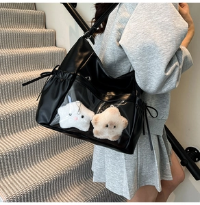 Detail of black faux leather ita bag with clear PVC window and plush star charms