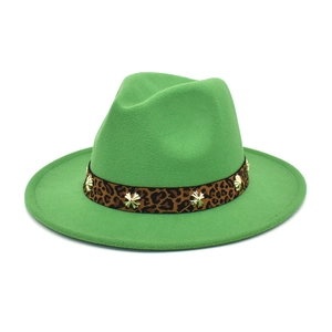 Detail of leopard print ribbon and gold clover stud on green wool fedora hat