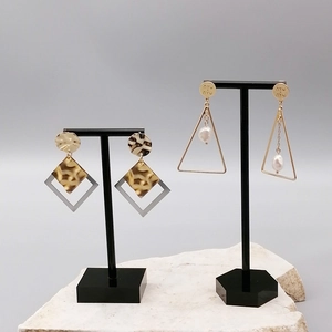 Detail of leopard print and pearl earrings on a black T-shape display stand