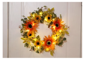 Detail of sunflower wreath with LED lights hanging on white door for autumn home decor