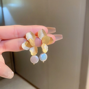 Gros plan détaillé de boucles d'oreilles fleurs dorées avec pétales brossés et perles