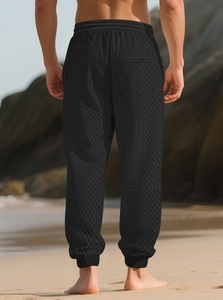 Detail of men's black waffle knit texture on drawstring joggers with elastic cuffs