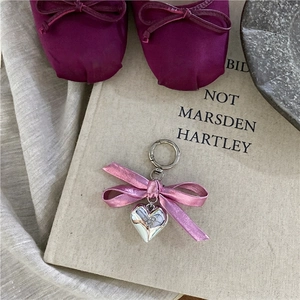 Detail of pink satin bow and polished silver heart pendant on a stylish keychain charm