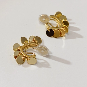 Detail of golden multi-disc clip-on earrings with protective silicone pads on white background