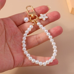 Elegant beaded pearl keychain with white flower pendant and golden clasp held by hand