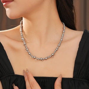 Close-up of elegant grey pearl beaded necklace with small star pendants on a model
