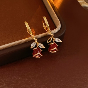 Détail de boucles d'oreilles rose en émail rouge avec crochets dorés et feuilles en zircone