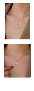 Detailed close-up of a shimmering gold anchor pendant with zircon stones on a chain