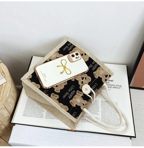 Detailed view of beige canvas tote with black bear print and white phone case