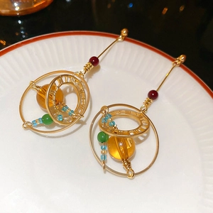 Detailed shot of vintage gold earrings with amber beads and Roman numerals on ceramic tray