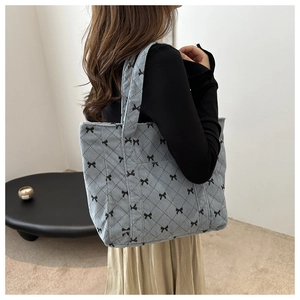 Detail of light blue corduroy tote bag with black bow print and diamond quilted stitching