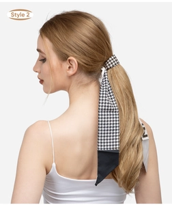 Detail of a houndstooth and black ribbon hair tie shown on a wavy ponytail