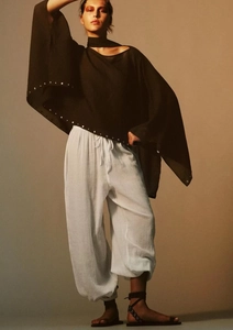 Detail view of Bohemian black poncho top featuring silver rivets and wide batwing sleeves