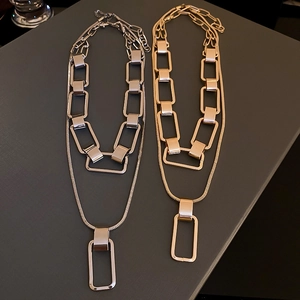 Detailed view of layered gold and silver chain necklaces with rectangle pendants