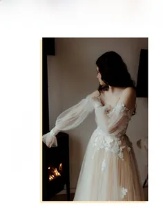 Detail of off-shoulder lace wedding dress with sheer lantern sleeves and floral applique