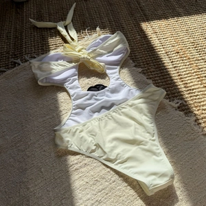Detail view of cream one-piece swimsuit with waist cutouts and halter neck ties