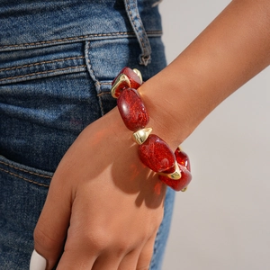 Close-up of red glitter acrylic beads and gold geometric links on a woman's wrist