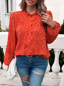 Detail of orange hollow lace shirt featuring a ruffle stand collar and button-up front