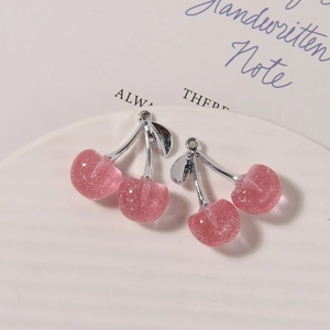 Detailed view of pink resin cherry charms with silver metal leaves for DIY jewelry making
