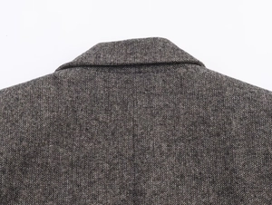 Macro shot of the collar detail and herringbone wool texture on a dark grey blazer