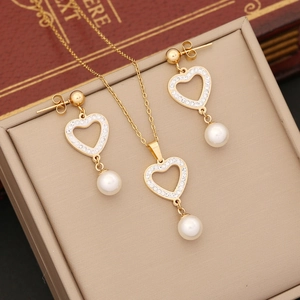 Golden heart jewelry set with white crystals and pearls on a beige display box