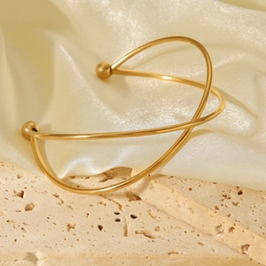 Detail view of 18k gold-plated crossed line bangle on silk and stone base