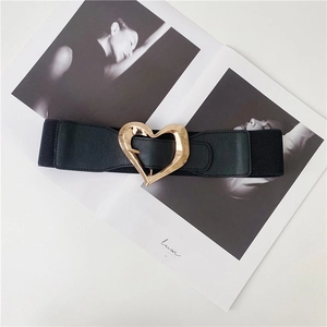 Close-up of black elastic waist belt with a golden irregular heart-shaped buckle detail