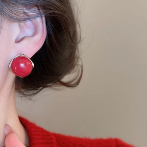 Close-up of red geometric stud earrings with silver borders worn by a model