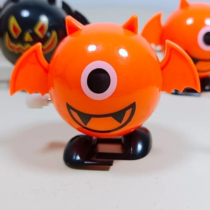 Close-up of orange Halloween wind-up bat toy with black wings and white knob