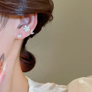 Detail of silver needle flower earring with pearl and zircon leaf on a female ear