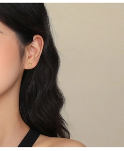 Primo piano di orecchini a cuore dorati indossati da una modella per mostrare lo stile