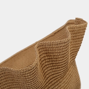 Macro shot of natural woven straw hat featuring unique ruffle edge and spiral texture