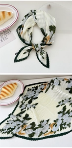 Detail of pleated silk scarf with green floral print and delicate scalloped edge