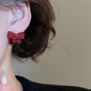 Macro shot of a red bow earring with a large square ruby on a model's earlobe