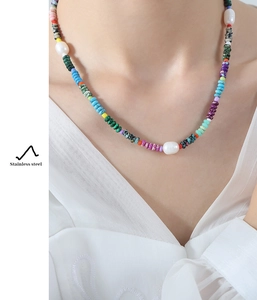 Detail of ethnic style necklace featuring colorful natural stones and white pearls on neck