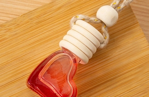 Close-up of heart-shaped glass bottle with red liquid and a wooden cap on wood surface