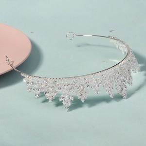 Close-up of a silver bridal crown featuring sparkling zircon stones on a blue background